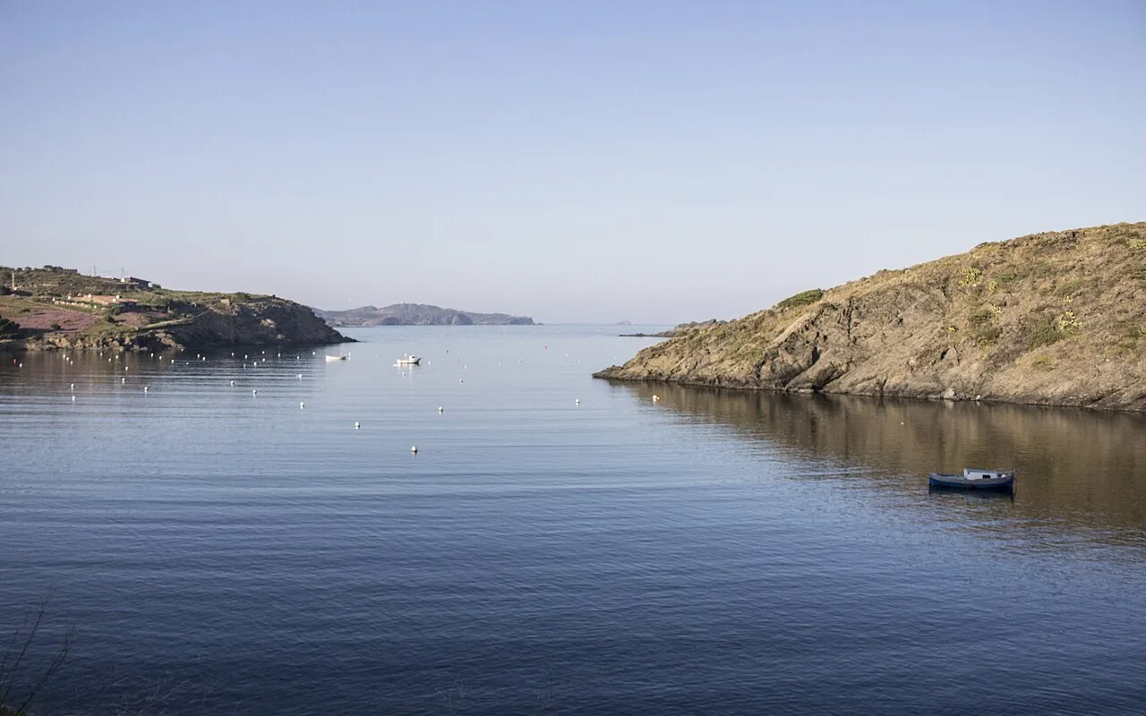 The calm bay of Portlligat with small boats at anchor and the low hills of Cap de Creus