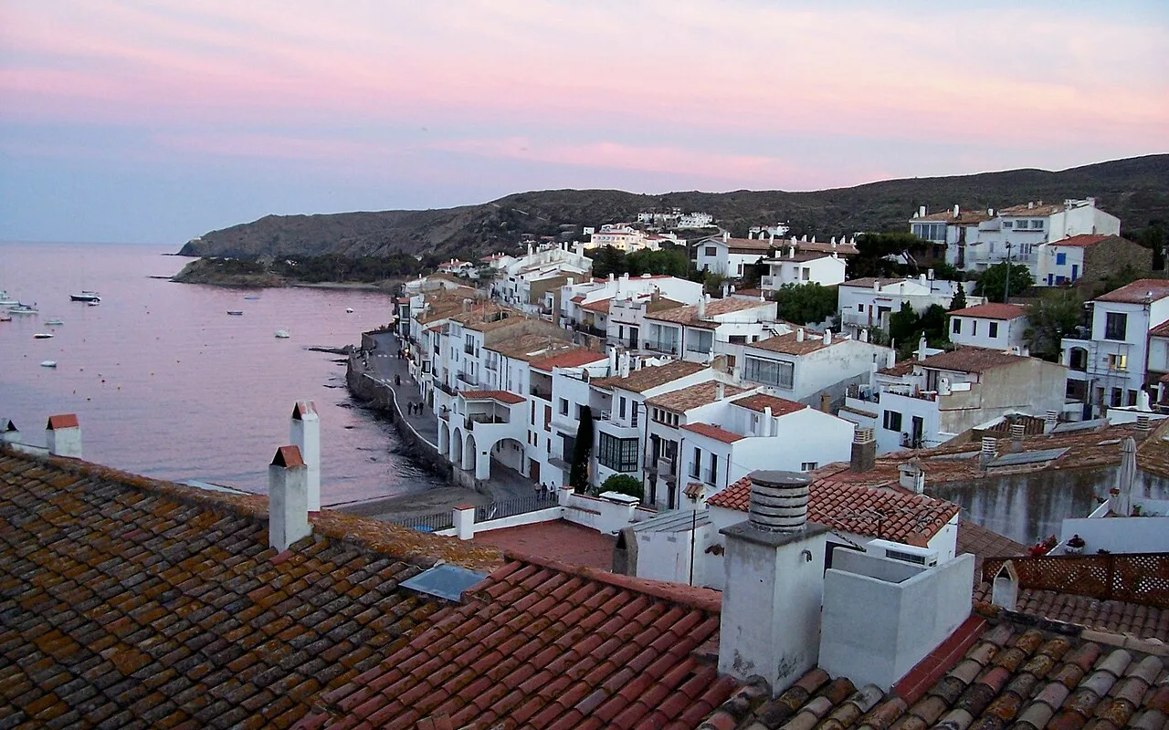 Whitewashed houses and terracotta roofs of Cadaqués above the sea at dusk